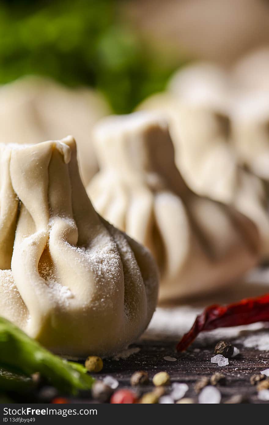 Georgian dumpling or Khinkali. Georgian homemade khinkali on wooden background. Side view, selective focus. With fresh greenery, spices and raw mushrooms.