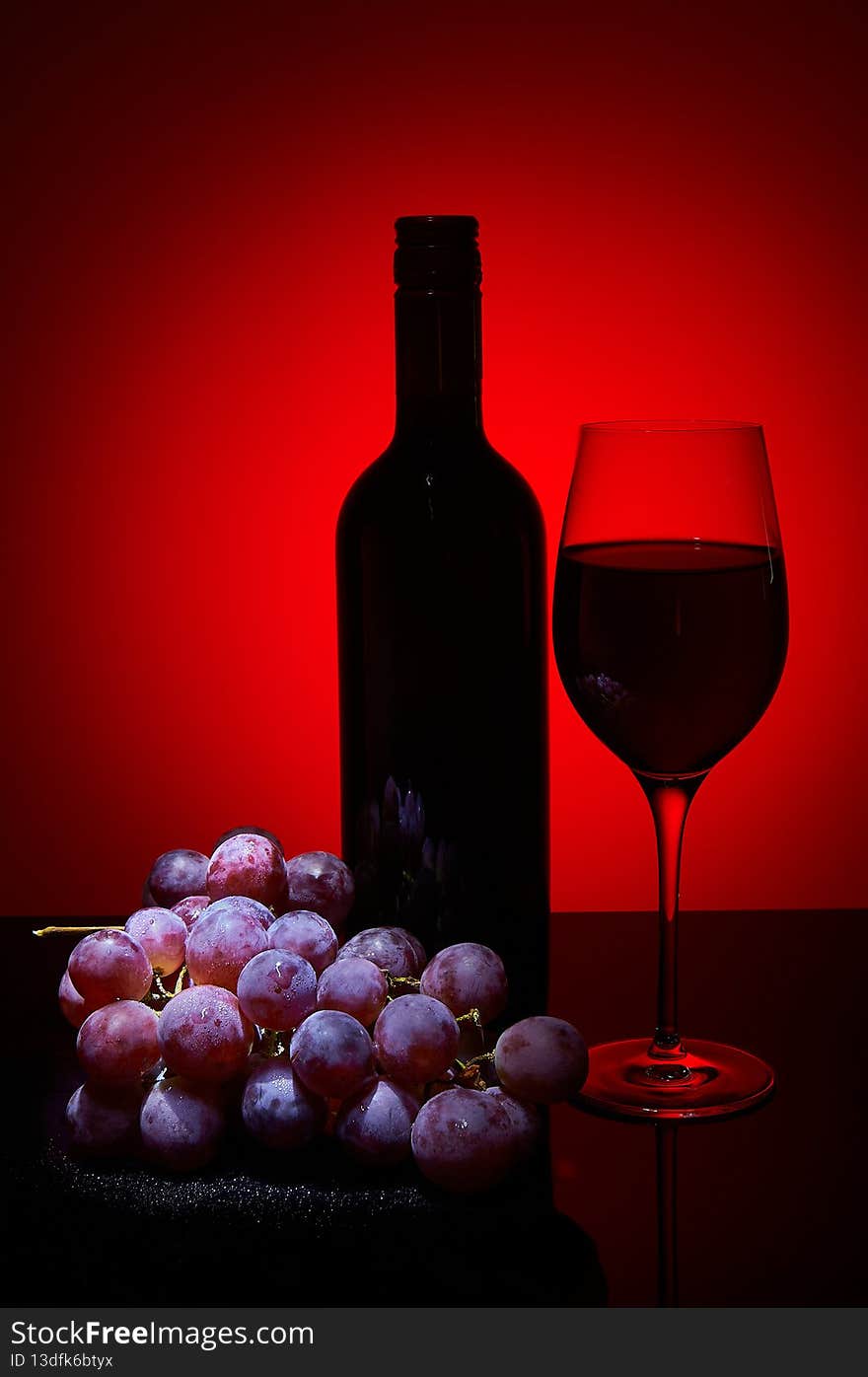 Wine bottle  and bunch of grapes on dark background
