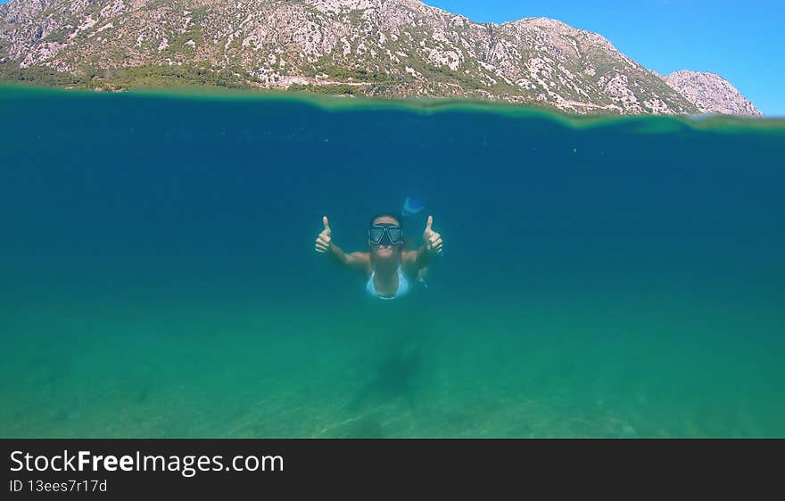 Woman snorkeling at the sea. Half view of ocean and mountains. High quality photo