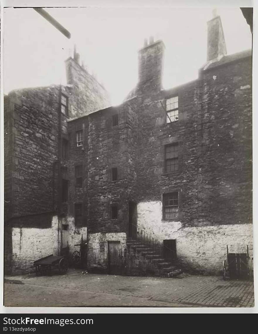 Photograph of the back view of a Three storey tenement building. There are three carts in front of the building and a set of stairs leading up to the first floor back entrance. The bottom section of the building is white washed. At one of the third storey windows there is an empty washing line.

digital.nls.uk/74506882. Photograph of the back view of a Three storey tenement building. There are three carts in front of the building and a set of stairs leading up to the first floor back entrance. The bottom section of the building is white washed. At one of the third storey windows there is an empty washing line.

digital.nls.uk/74506882