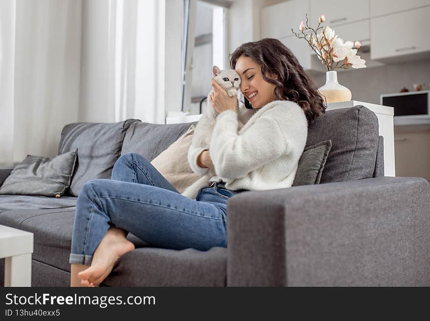 Sweet friend. Young woman in white sweater and her cat at home