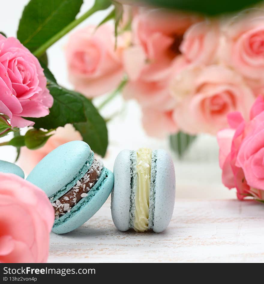 Stack of blue macarons on a white table and pink rosebuds, delicious dessert