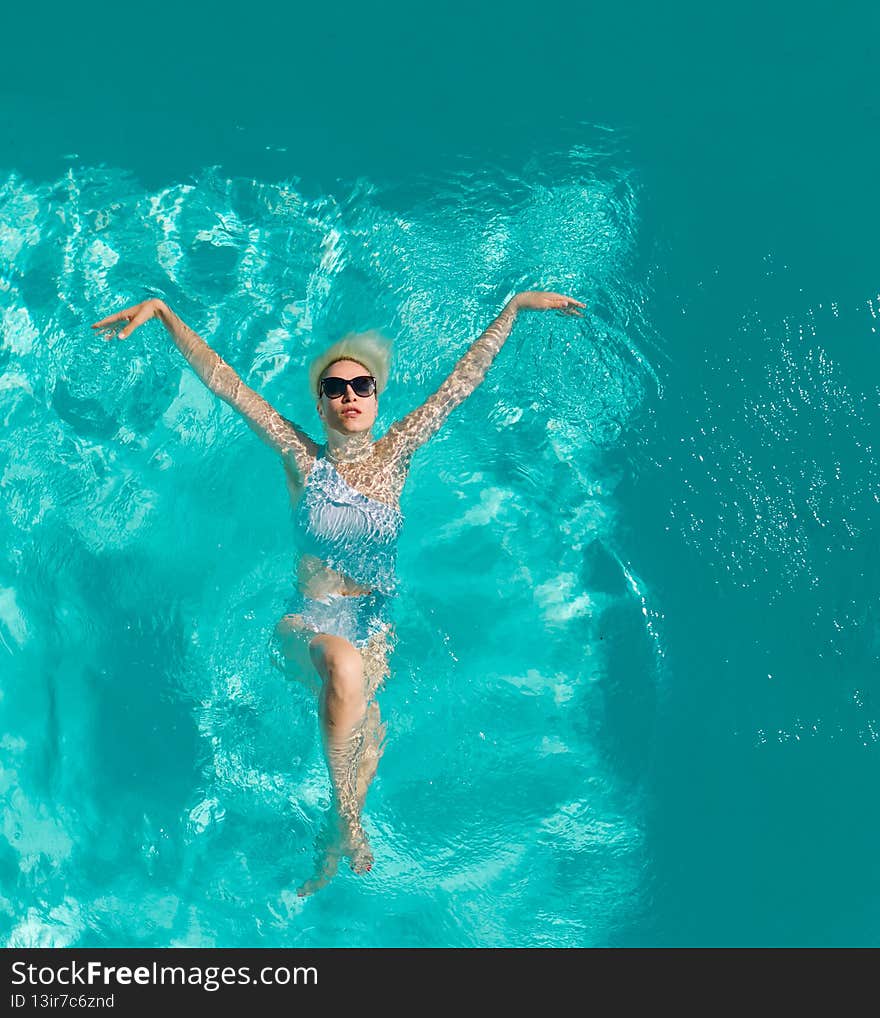 Young beautiful sexy girl enjoying swimming in the private pool and relaxing in the sun. Summertime