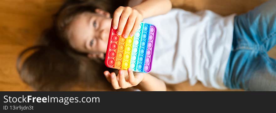 Anti stress sensory pop it toys in a children`s hands. a little happy kid girl plays with a simple dimple toy at home. toddler ho