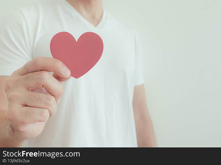 Man in white t-shirt shows pink heart shape in concept of love and Valentine. Man in white t-shirt shows pink heart shape in concept of love and Valentine.