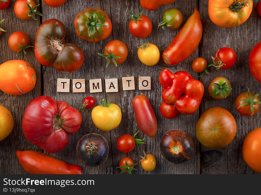 Summer harvest of tomatoes of different varieties and colors on a wooden table top view. Multi-colored vegetables -