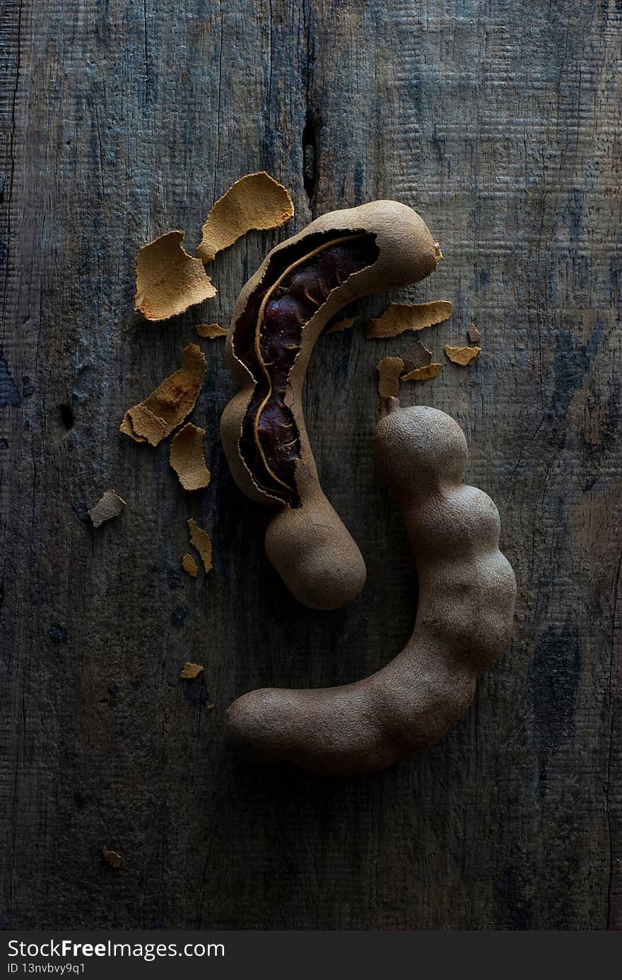 Tamarind fruit on a rustic wooden floor, top view, close up, dark tone. Tamarind fruit on a rustic wooden floor, top view, close up, dark tone.