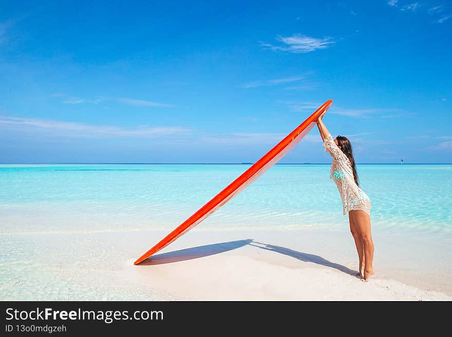 Beautiful surfer woman ready to surfing in turquoise sea with red paddle board at exotic vacation. Beautiful surfer woman ready to surfing in turquoise sea with red paddle board at exotic vacation
