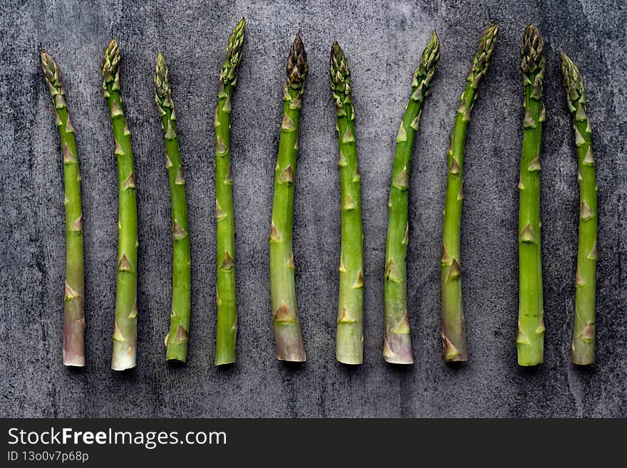 Green fresh raw asparagus on concrete background. Bunch of fresh asparagus top view on gray concrete background.
