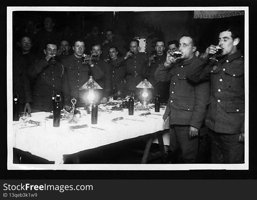 Soldiers at Christmas. The men are raising their glasses. 

The caption on the previous photograph in the sequence reveals that the glasses were filled with beer, not wine. There was not much cheer for the soldiers on the front line. It is difficult not to wonder whether this picture was not set up by the photographer as a piece of reassuring propaganda for publication in the newspapers back home.

[Original reads: &#x27;Drinking the King&#x27;s health back in their billets.&#x27;]

digital.nls.uk/74545982