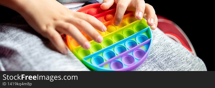 anti stress sensory pop it toys in a children`s hands. a little happy kid boy plays with a simple dimple toy in the car. toddler