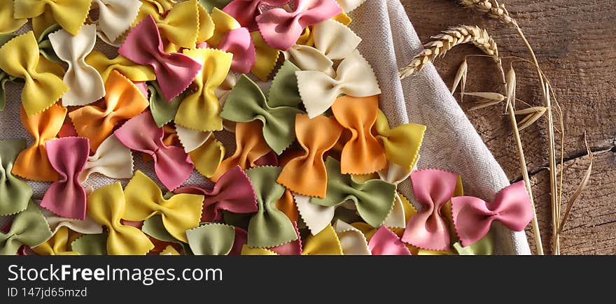 Italian pasta Farfalle background with rye on old wood background. Bow-tie colourful pasta pattern. Horizontal Flat lay top view