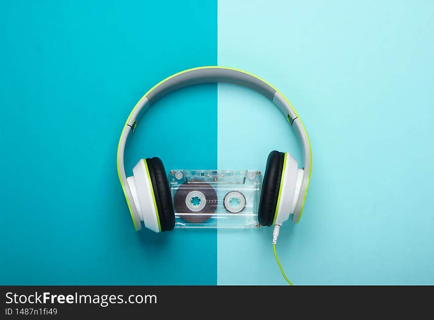 Stylish wired stereo headphones with audio cassette on yellow background. Music lover. Retro 80s