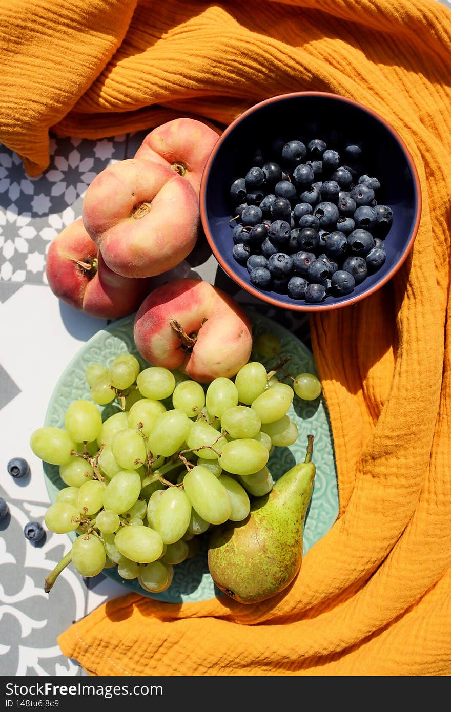 Still life with fresh seasonal fruit. Healthy eating concept. Peaches, pears and berries on grey tiled table Breakfast in the garden. Sunny day photo. Still life with fresh seasonal fruit. Healthy eating concept. Peaches, pears and berries on grey tiled table Breakfast in the garden. Sunny day photo.