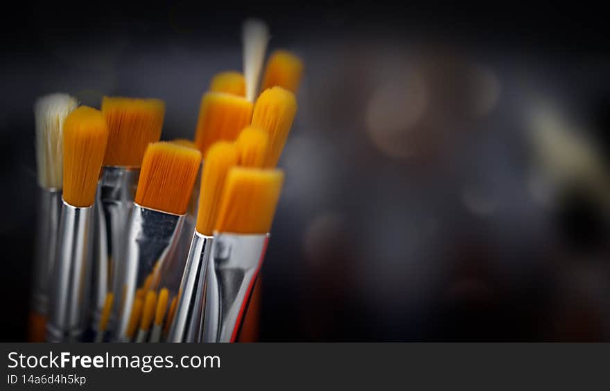 Artist`s brushes for painting. Close up of different new painting brushes on dark background with bokeh, soft focus. Artist`s brushes for painting. Close up of different new painting brushes on dark background with bokeh, soft focus