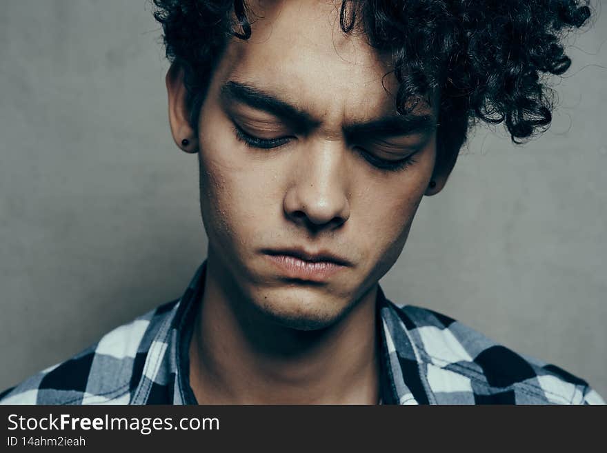 guy in plaid shirt curly hair serious facial expression close up