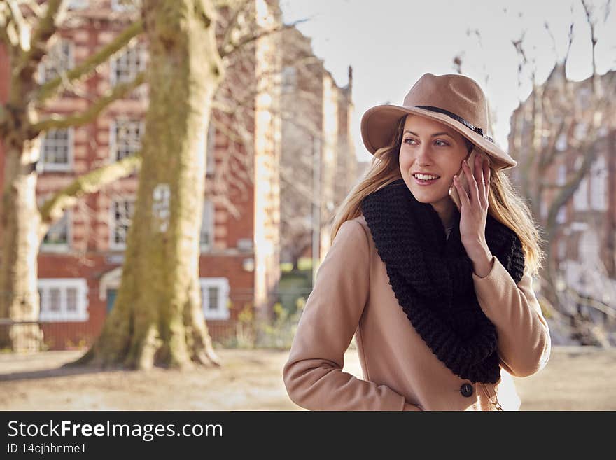 Woman In City Park Waiting For Date To Arrive Making Call On Mobile Phone