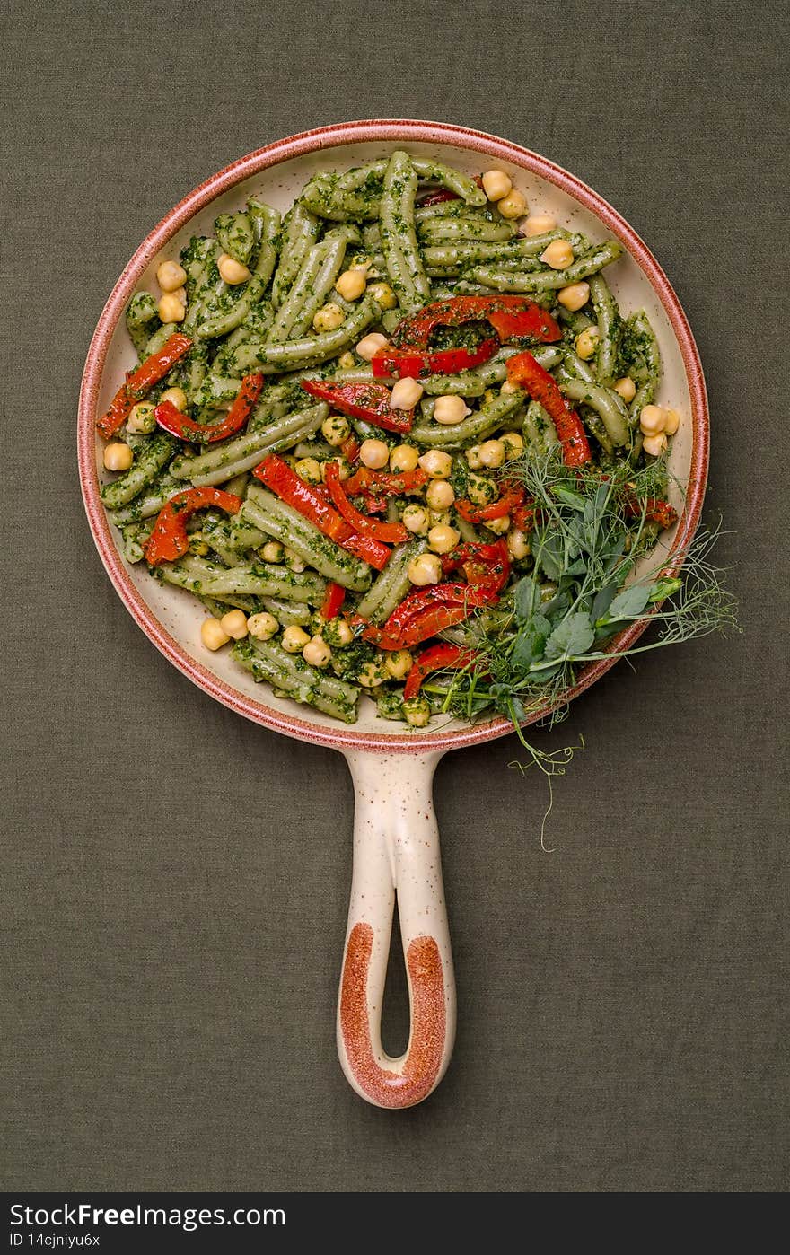 Green pasta with chickpeas, pepper and pesto sauce on a textile background. Top view. Selective focus