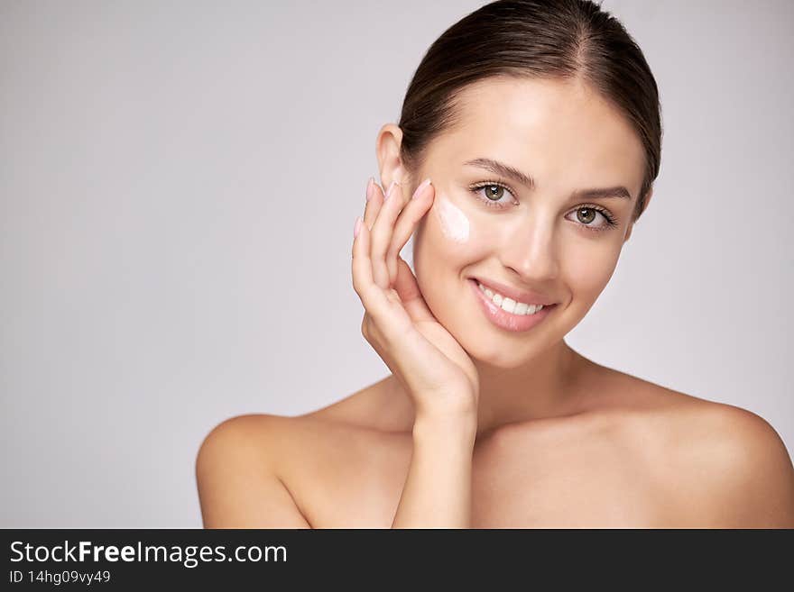 Beautiful Young Woman with Clean Fresh Skin standing over light grey background