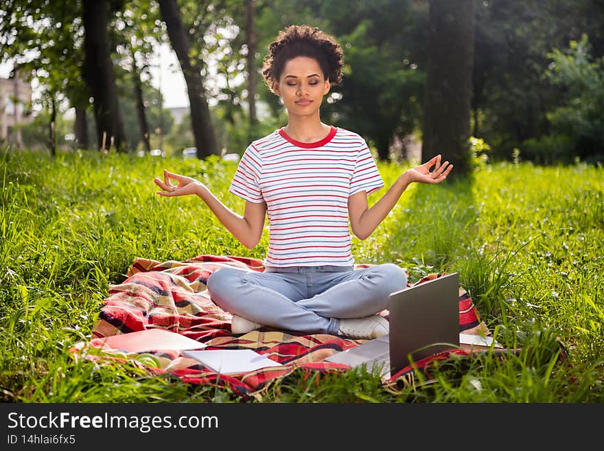 Full length photo of young african woman happy positive smile rest relax meditate om zen yoga break outdoors