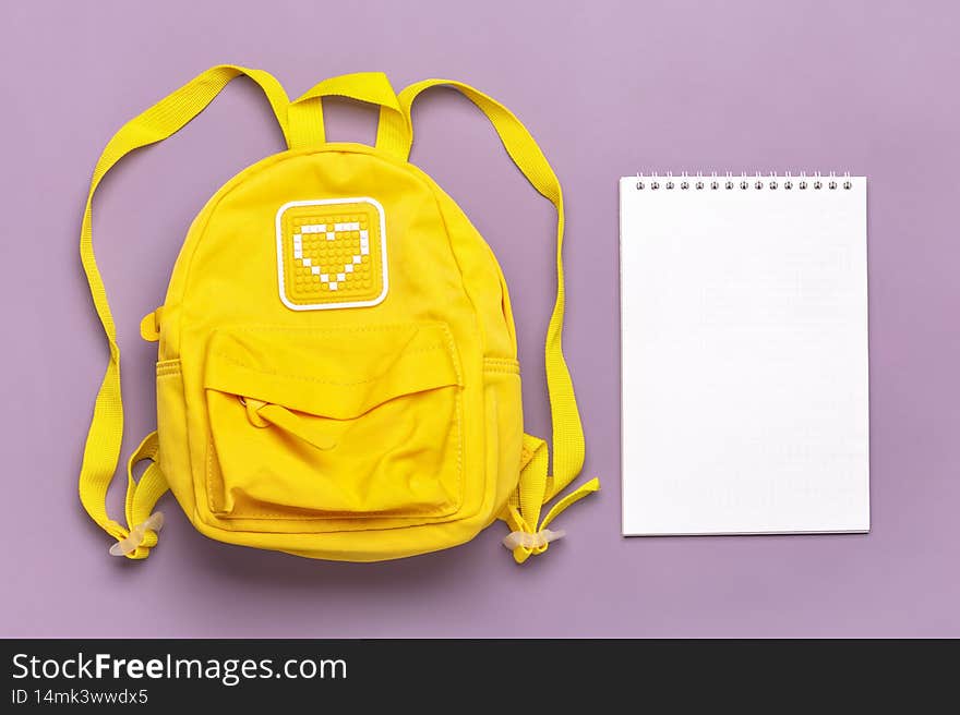 Back to school Open notepad, education concept. Yellow backpack isolated on violent background. Top view Flat lay composition