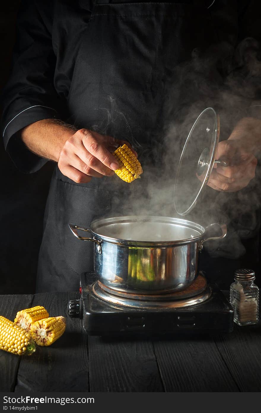 A professional chef cooks corn. Close-up of a chef is a hand while cooking in a restaurant kitchen.