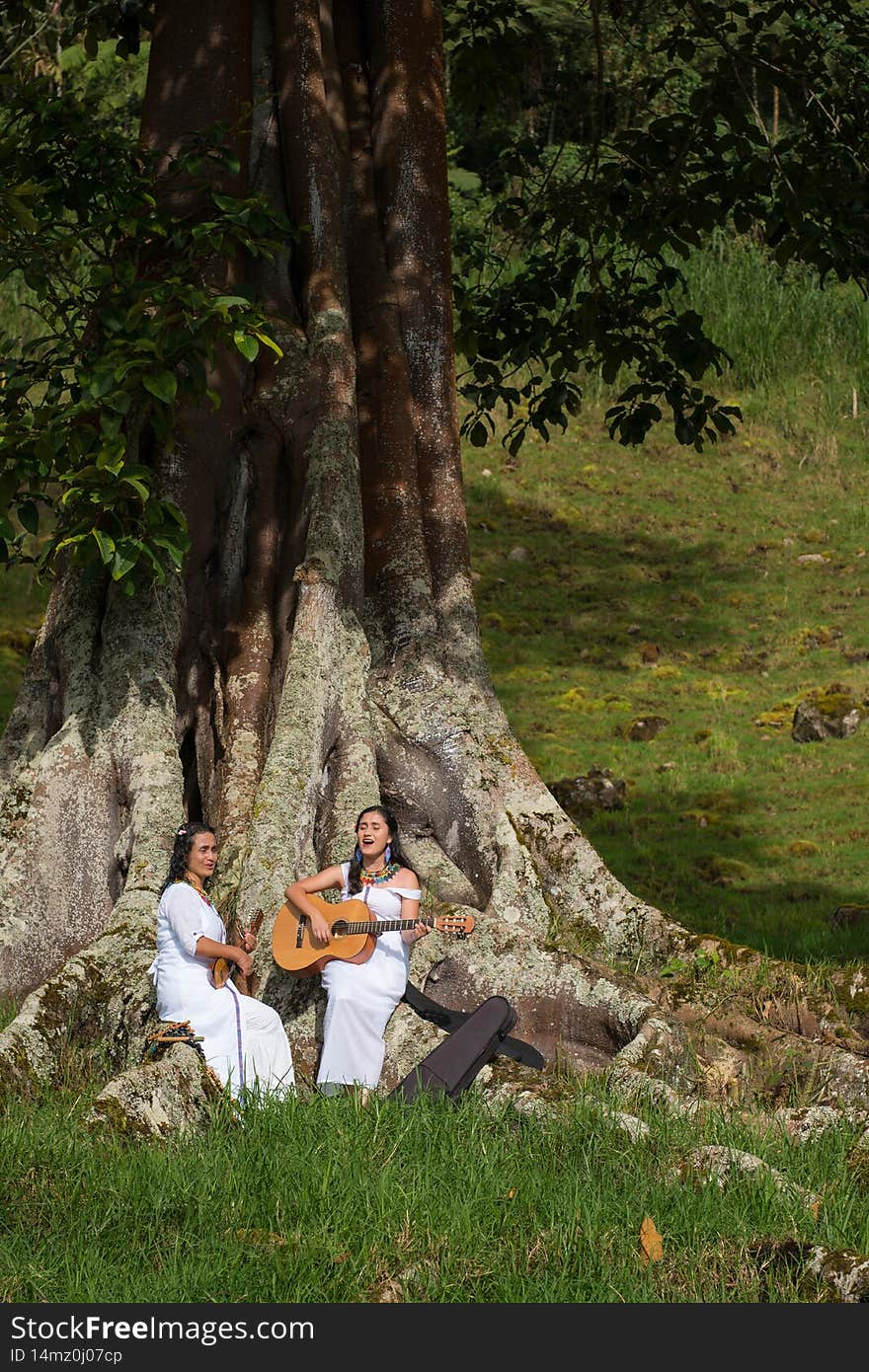 Indigenous women with instruments singing in nature. Colombian ethnic group singing