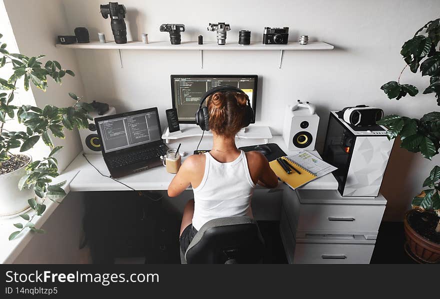 Girl programmer at modern developer workplace for writing code with white computer desktop and comfy armchair. Freelancer at home office. Girl programmer at modern developer workplace for writing code with white computer desktop and comfy armchair. Freelancer at home office.