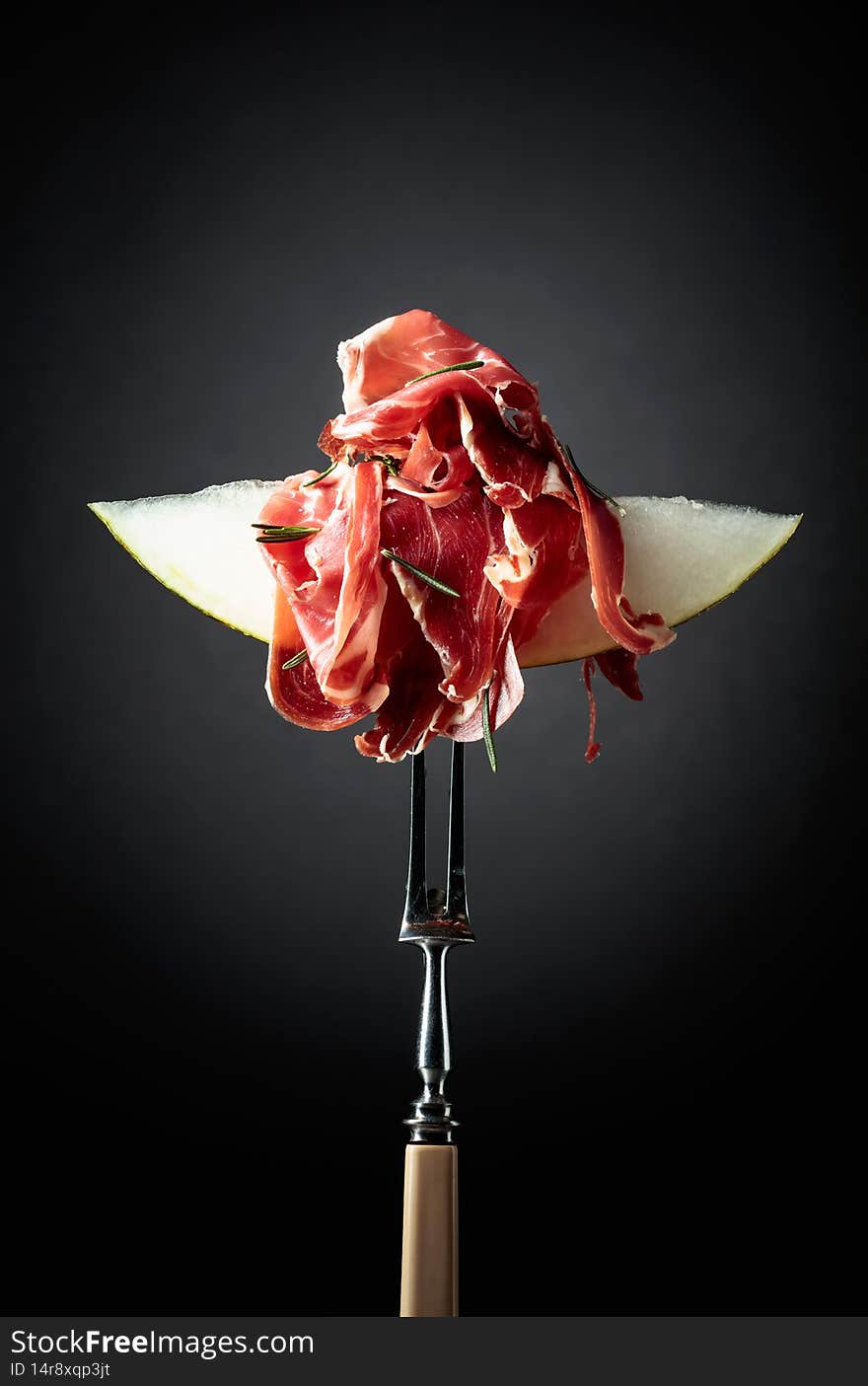 Melon With Prosciutto And Rosemary On A Black Background