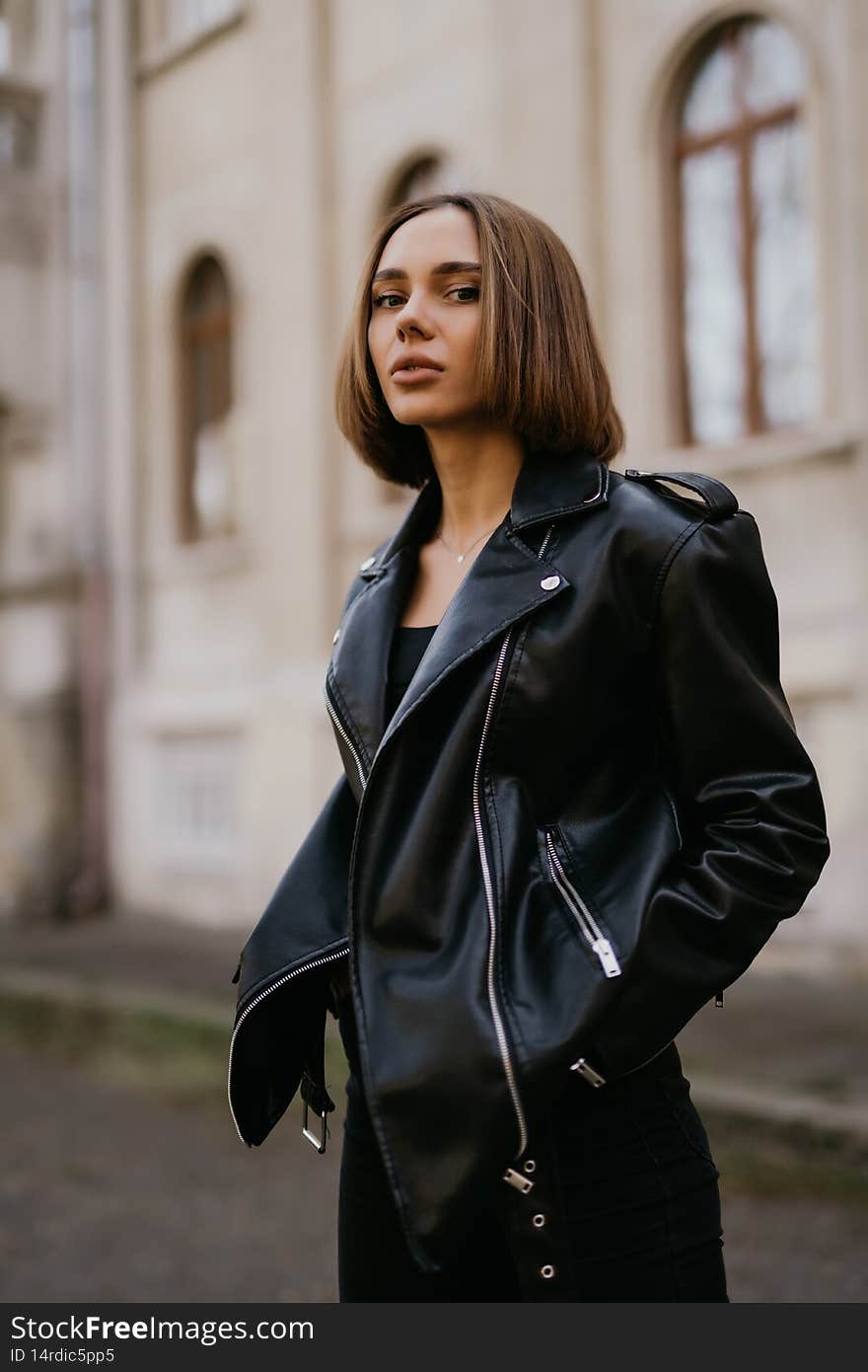 Young fashion blond woman in leather jacket on the city street