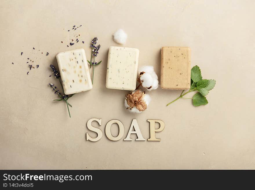 Natural soap bars - lavender, cotton, patchouli - ingredients and wooden letters on natural stone background, flat lay