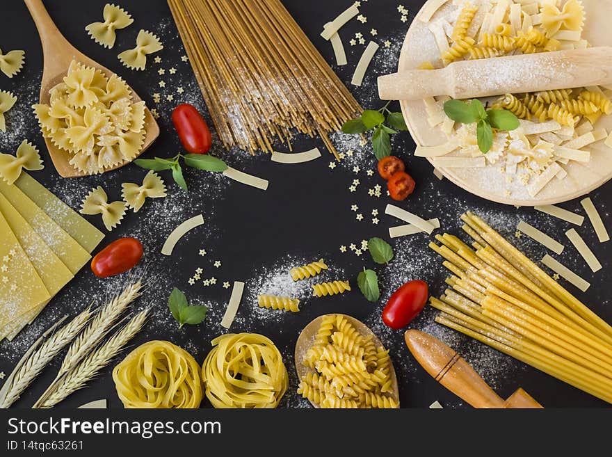 Various of pasta or macaroni on black surface with fresh mint,cherry tomatoes and copy space on centre. Various of pasta or macaroni on black surface with fresh mint,cherry tomatoes and copy space on centre