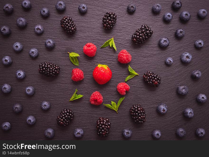 Ripe berry- blackberries, blueberries and raspberries and mint leaves, beautifully laid out