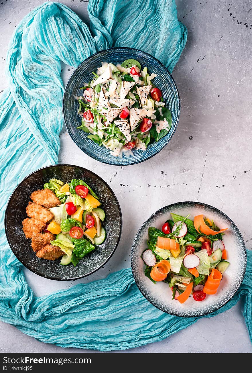 Fresh vegetable salads on table flat lay. Top view on kitchen table with three dishes Restaurant, menu, buffet concept
