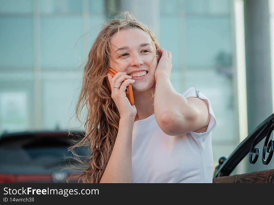 A young woman is sitting on a bench with a smartphone in white clothes