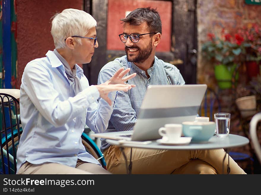 Senior female explaining something with hand gesture to a young adult beardy man