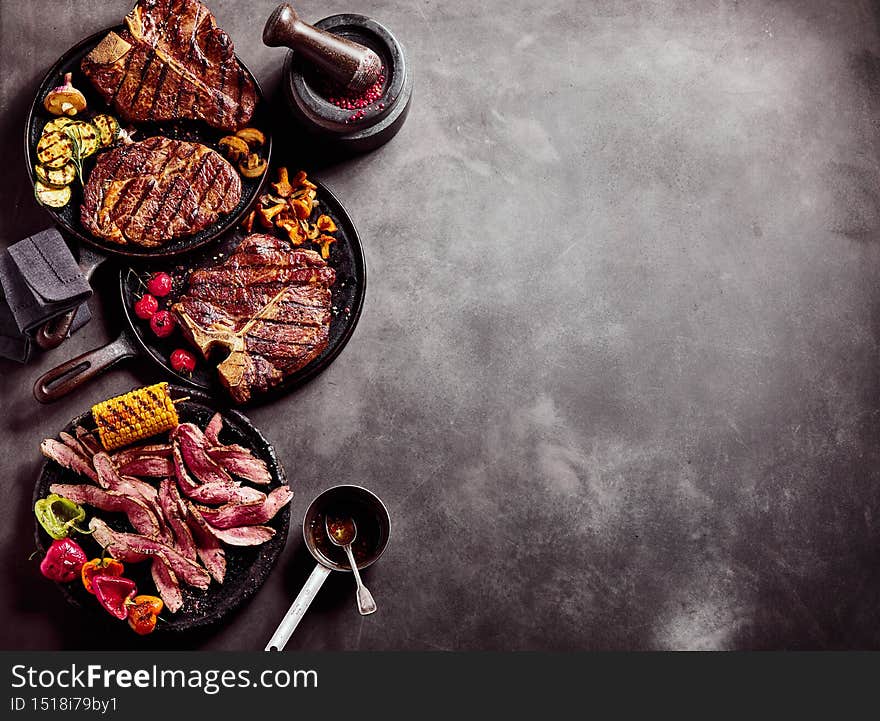 Delicious steaks on pans on table