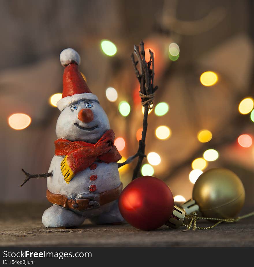 Christmas snowman decoration against the backdrop illumination and fir tree.