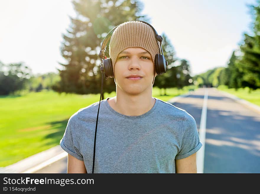 Portrait of teenage hipster in knitted hat with headphones looking in camera