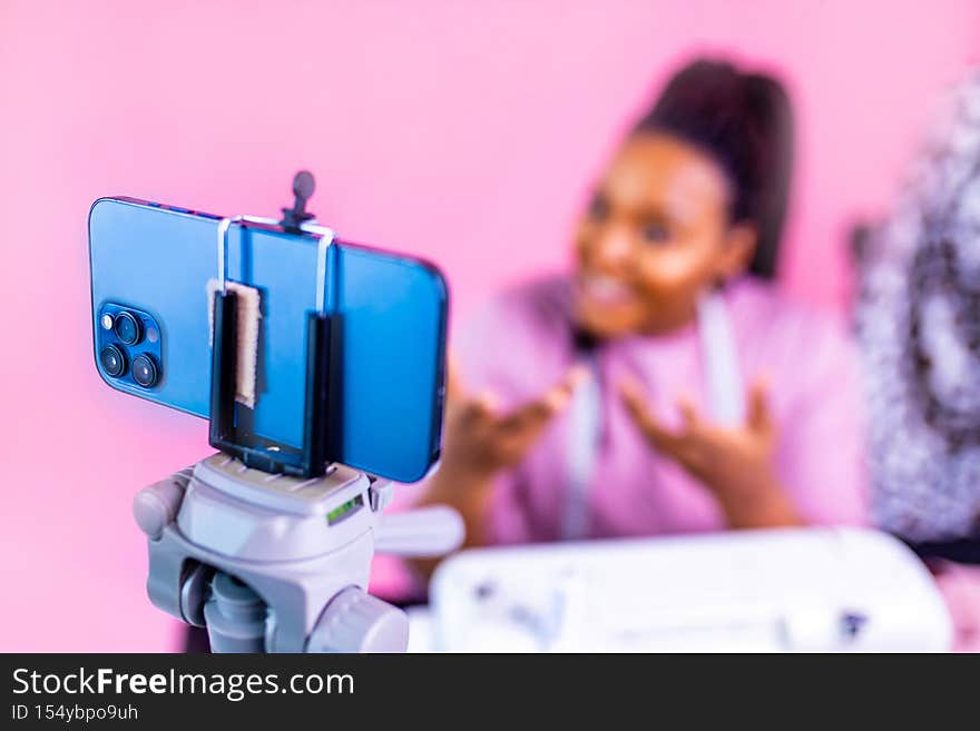 blogger woman demonstrates sewing equipment blog about sewing in studio on pink wall background.