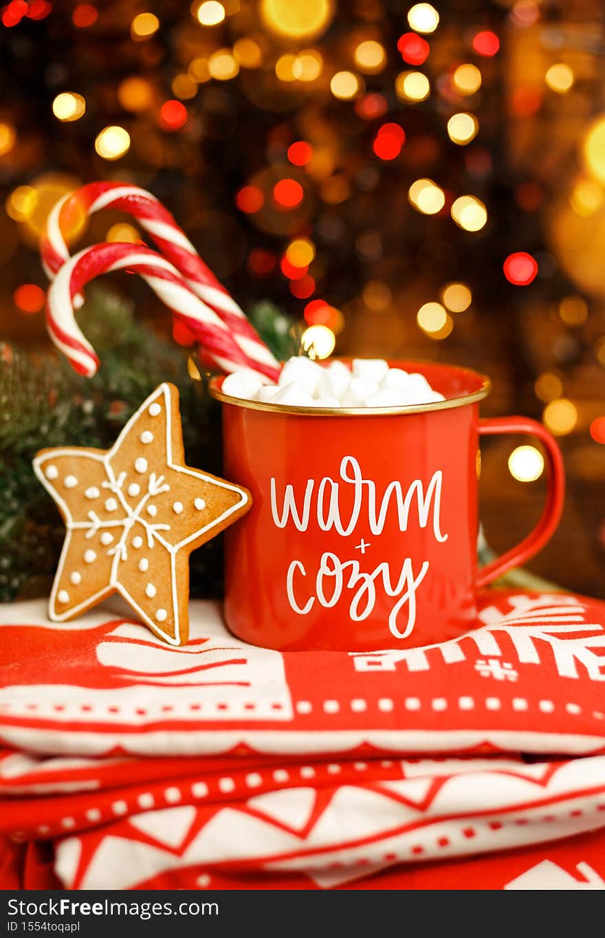 Cup of tasty cocoa with Xmas candy cane on wooden table