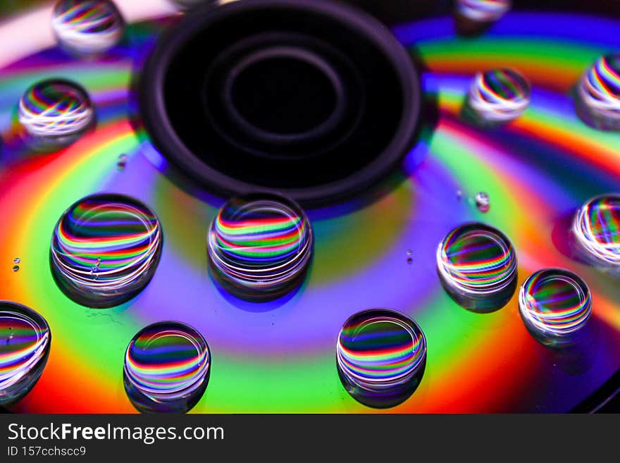 Closeup of a compact disc with rainbow color reflection and water drops