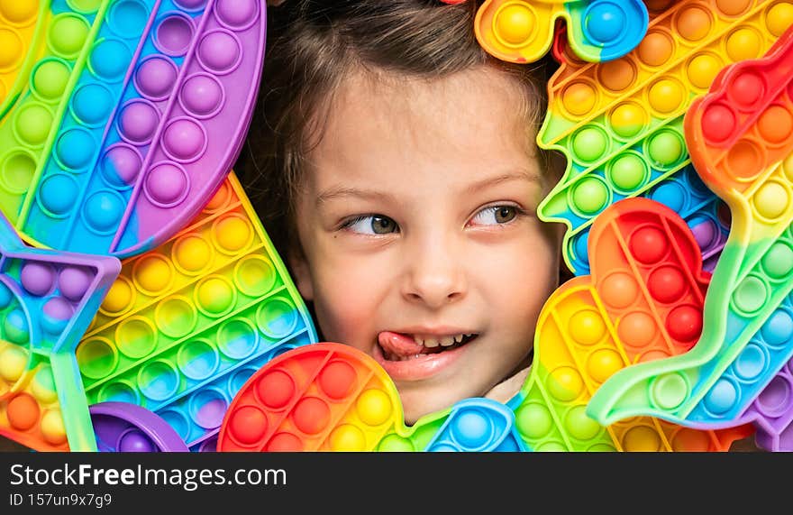 Little girl,kid,child head among many,lots of colorful pop it. Children play. Trendy silicone antistress colorful sensory push toy
