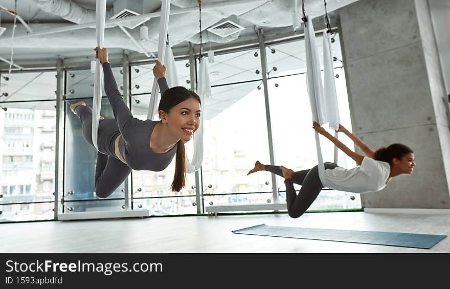 Smiling diverse women have stretching fly yoga class
