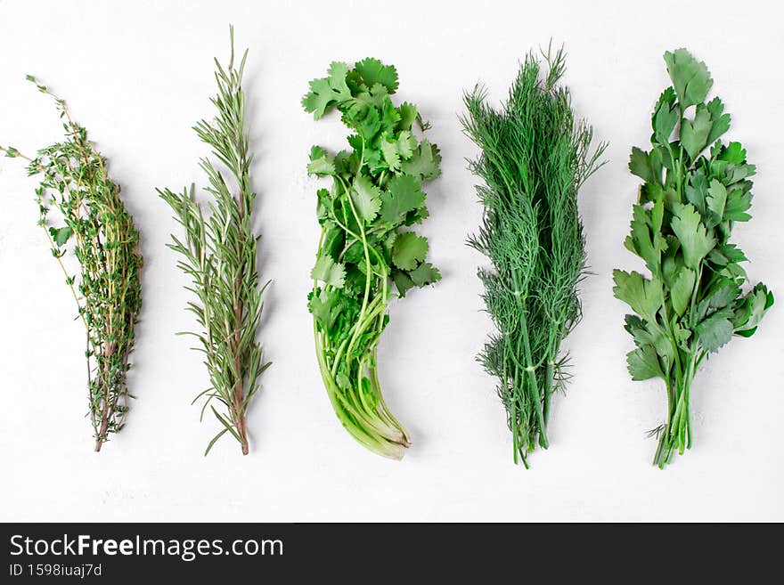 Parsley, cilantro, thyme, rosemary and dill on the white table. Bunches of fresh aromatic herbs. Top view. Parsley, cilantro, thyme, rosemary and dill on the white table. Bunches of fresh aromatic herbs. Top view