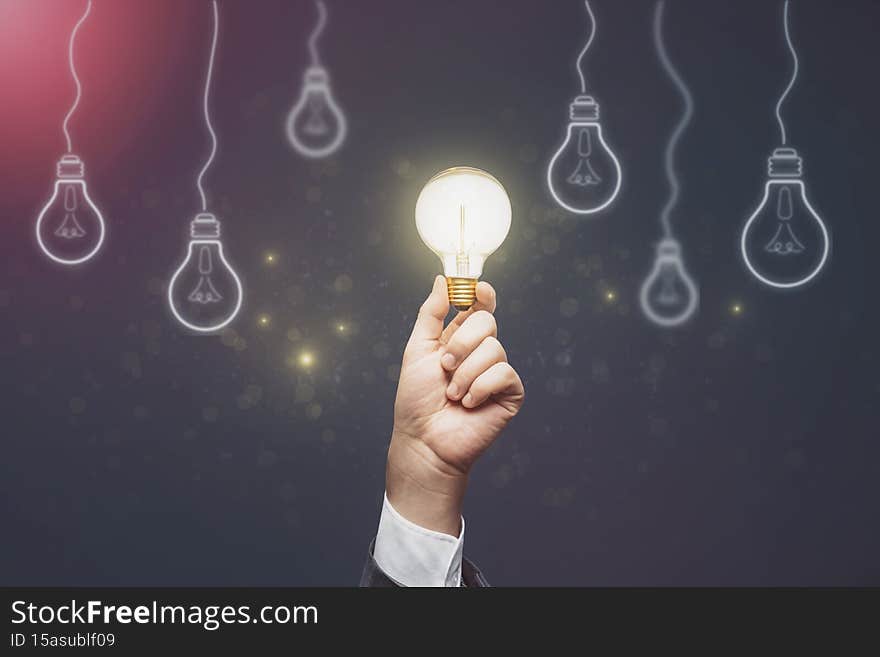 Businessman hand holding abstract light bulbs on dark background. Idea  concept