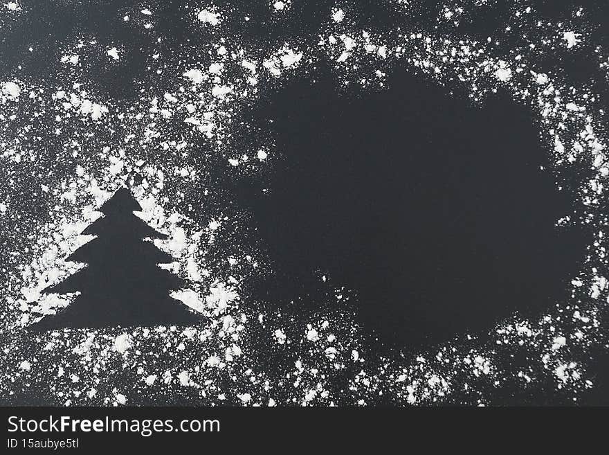 Top view of pine tree shape and snow around made from white flour, copy space, place for inscription.