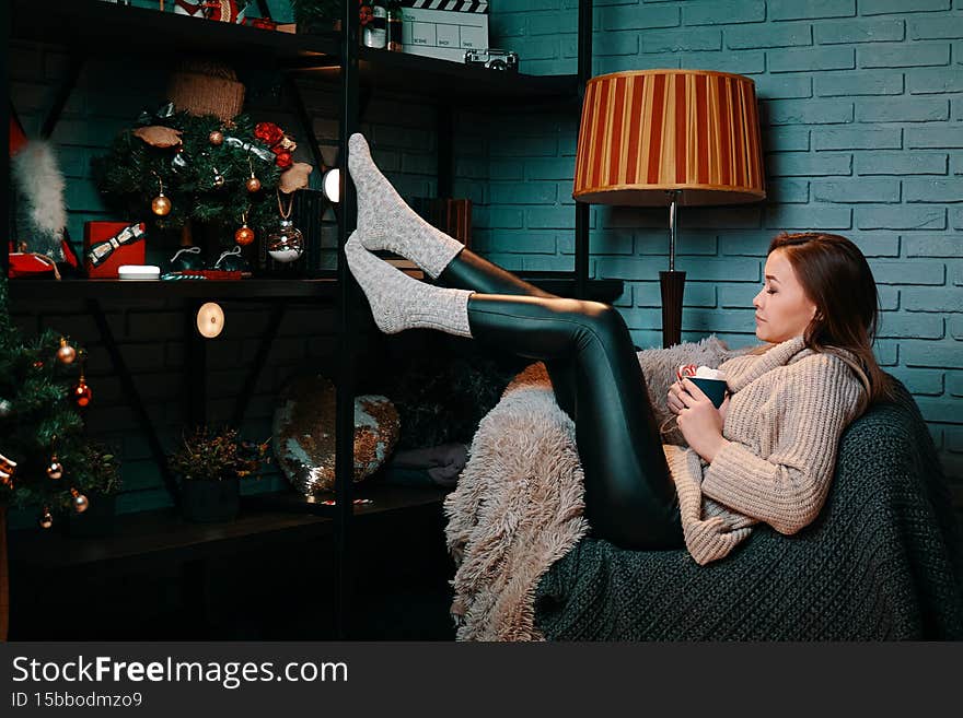 Woman with cup of cocoa sitting on chair.