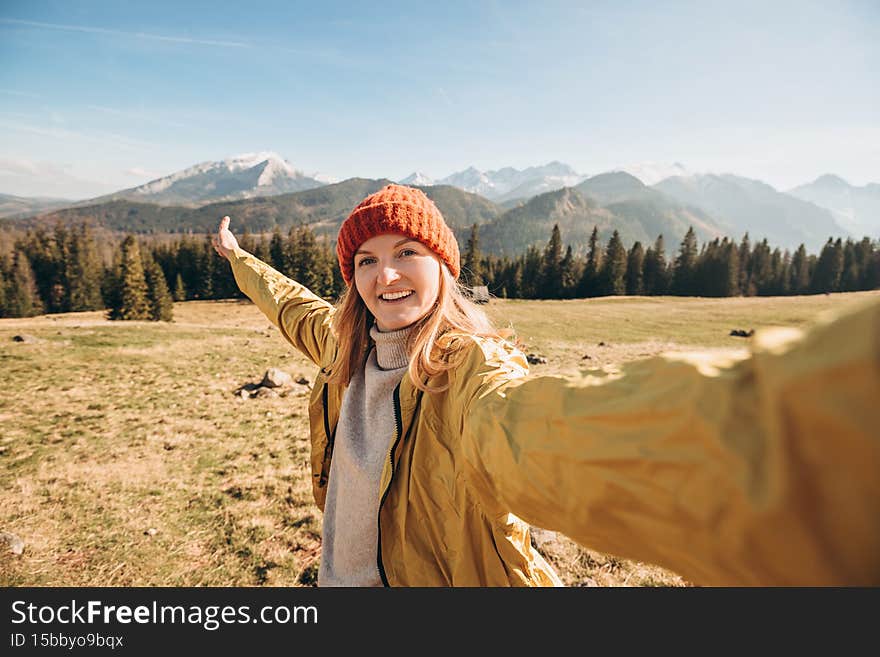 Young woman making selfie photo high in the snow mountains enjoying the view. Freedom, happiness, travel and vacations
