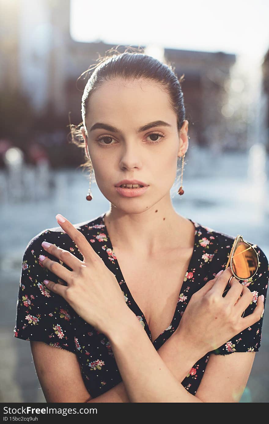 Portrait of a stylish young woman. Brunette with ballerina hairstyle in sundress posing on street. Selective focus